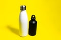 Top view of two reusable eco, steel and aluminum, thermo water bottle, white and black color, on yellow background. Royalty Free Stock Photo