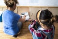 Top view. Two women loading paint roller in paint tray. Preparing to paint house walls white