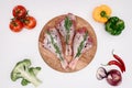 top view of uncooked chicken legs with rosemary on cutting board with raw vegetables near Royalty Free Stock Photo