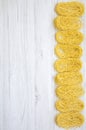 Top view, uncooked pasta tagliolini on white wooden table. Flat lay, above, overhead.