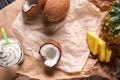 Top view of unfolded paper on the table with splitted coconut, pineapple with slices and creamy milk cocktail Royalty Free Stock Photo