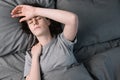 Top view on unhappy young woman with closed eyes lying in bed, touching forehead hand having a suffering migraine, feeling unwell Royalty Free Stock Photo