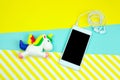 unicorn and smartphone with earphones on a bright blue and stripped yellow background