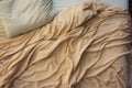 Top view of an unmade beige bed with a crumpled sheet, blanket and pillows Royalty Free Stock Photo
