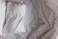 Top view of the unmade white bed sheet and pillow