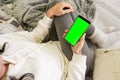 Top view of unrecognizable young woman on sofa holding smartphone with green screen blank display for copy space. Caucasian female Royalty Free Stock Photo