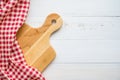 Top view of unused brand new brown handmade wooden cutting board and red napkins on white wooden table background - Food and kitch