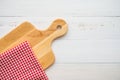 Top view of unused brand new brown handmade wooden cutting board and red napkins on white wooden table background - Food and kitch Royalty Free Stock Photo