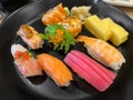 Top view of variety of sushi and rolls served on black plate. Plenty of nigiri, maki, and roll with tuna, salmon, shrimp Royalty Free Stock Photo