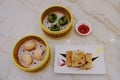 Top view of a variety of traditional dim sum dishes on dining table in restaurant. Dumplings in bamboo steamer baskets, and pan