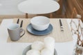 Top view of various dishware on the white dinner table - ceramic plates, cup, fork, spoon and knive