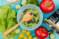 top view of vegetable salad with lettuce cucumber tomato coriander and grater with wooden spoon on blue background