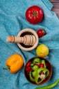 top view of vegetables as whole and sliced peppers and tomatoes with lemon and black pepper in garlic crusher on blue cloth