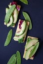 Top view of vegetarian toasts with avocado, green peas and salad, on dark navy blue background.