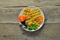 Top view of vegetarian zucchini waffles with herbs on a plate with fresh tomatoes, basil and parsley on a wooden background