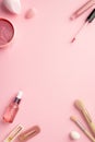 Top view vertical photo of beauty blenders pink eye patches with special spoon lip gloss glass dropper bottle makeup brushes and Royalty Free Stock Photo