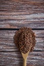 Top view vertical shot of a wooden spoon overflowing with brown lentils on a wooden table