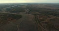 A top view of a very large open-pit mine; a very large mine and factory are located nearby