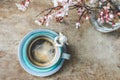 Top view of a vintage blue cup of coffee with an angel figurine and a vase with blooming tree branches on wooden background Royalty Free Stock Photo