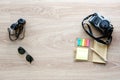 Top view vintage camera, sunglasses, binoculars and notepad with pen on the wooden background with copy space for adding some text