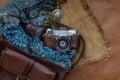 Top view of a vintage photo camera and a brown leather bag with scarf, glasses and pocket watch on sack cloth background Royalty Free Stock Photo