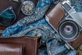 Top view of a vintage photo camera and a brown leather bag with scarf, glasses and pocket watch on sack cloth background Royalty Free Stock Photo