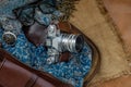 Top view of a vintage photo camera and a brown leather bag with scarf, glasses and pocket watch on sack cloth background Royalty Free Stock Photo