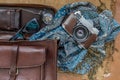 Top view of a vintage photo camera and a brown leather bag with scarf, glasses and pocket watch on sack cloth background Royalty Free Stock Photo