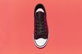 Top view of vintage sneaker shoe on coral pink background.