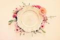 Top view of vintage white empty plate over spring flowers. Flat lay.