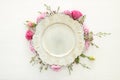 Top view of vintage white empty plate over spring flowers. Flat lay.