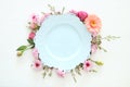 Top view of vintage white empty plate over spring flowers. Flat lay.