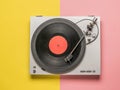 Top view of a vinyl record player on a red and yellow background