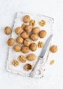 Top view walnut in endocarp, bowl with drupe in shell on white wooden cutting board. White background, overhead, close up Royalty Free Stock Photo