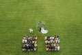 Top view of the Wedding ceremony in a green field with guests sitting on chairs. Wedding venue on the green lawn