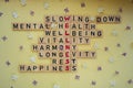 Top view of WELLNESS word on yellow background with flowers. Minimalism creative crossword puzzle concept. Message of