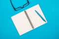 Top view of white blank notepad with pencil and glasses on isolated blue background Royalty Free Stock Photo