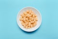 Top view of white bowl with corn puffs on blue background. Royalty Free Stock Photo