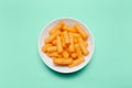 Top view of white bowl with corn puffs on green background. Royalty Free Stock Photo