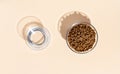 Top view of white bowl with dry kibble cat food and wateer on beige background. Royalty Free Stock Photo