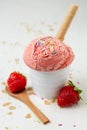 Top view of white bowl with strawberry ice cream and waffle, caramel chips on white table with strawberries Royalty Free Stock Photo