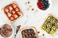 Top view of white bread toast sandwiches with chocolate hazelnut spread decorated with fresh summer berries: strawberries, Royalty Free Stock Photo