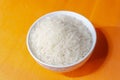 Top view of a white ceramic bowl with raw basmati rice on orange back Royalty Free Stock Photo