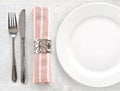 Top view white ceramic empty dish with silver fork and knife and napkin on the white tablecloth. Royalty Free Stock Photo