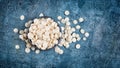 Top view of white chocolate drops or morsels in bowl on blue background