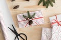 Top view of a white christmas gifts surrounded with paper roll, leaves and twine on a wooden table