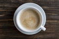 Top view a white cup of cappuccino with milk foam coffee on wooden table background at morning, closeup Royalty Free Stock Photo