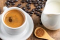 Top view of white cup with coffee on wooden table with coffee beans, wooden spoon with brown sugar and jug of milk, Royalty Free Stock Photo