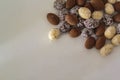 Top view of white, dark and cocoa Chocolate almonds on white table