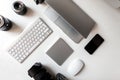 Top view of the white desktop on which lies the professional lenses to the camera, laptop, keyboard, telephone, wireless mouse Royalty Free Stock Photo